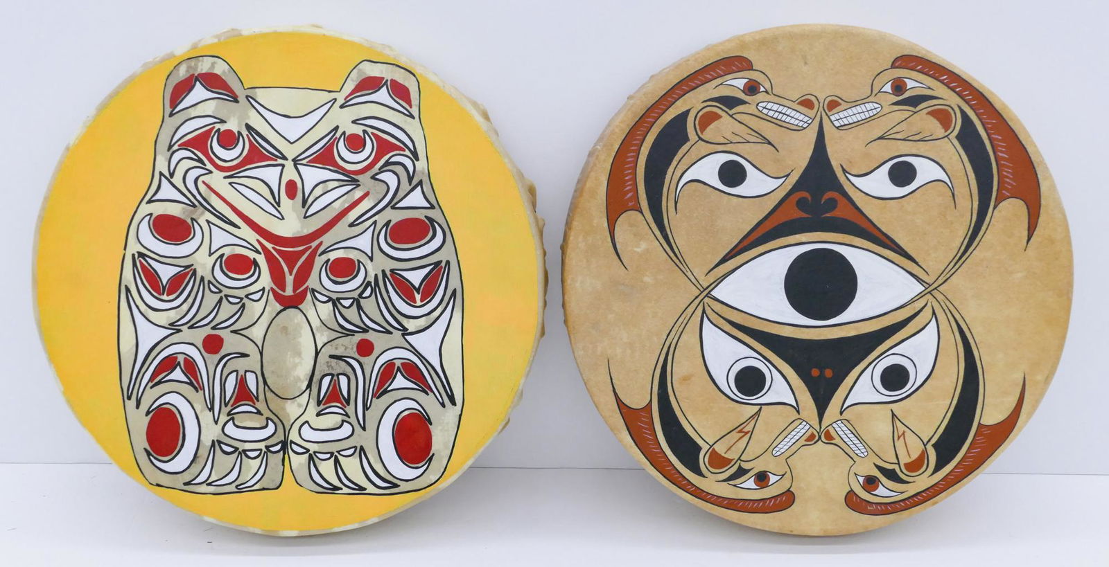 2pc Laurie Foster Ojibwe Painted Drums: 2pc Laurie Foster (20/21st Cent. Ojibwe) Painted Drums 16'' Approx. Includes a polychrome painted u-form ''Serpent and Their Keeper'' drum and one with a golden owl. Signed on interior. Excellent cond