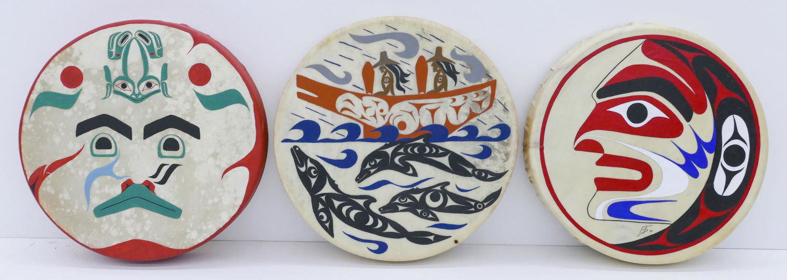 3pc Northwest Coast Native Polychrome Painted Drums: 3pc Northwest Coast Native Polychrome Painted Drums 16'' Approx. Includes a painted u-form mask drum signed with ''FTD'' initials, unsigned ''Homeward'' drum with dolphins and natives in canoe, and an