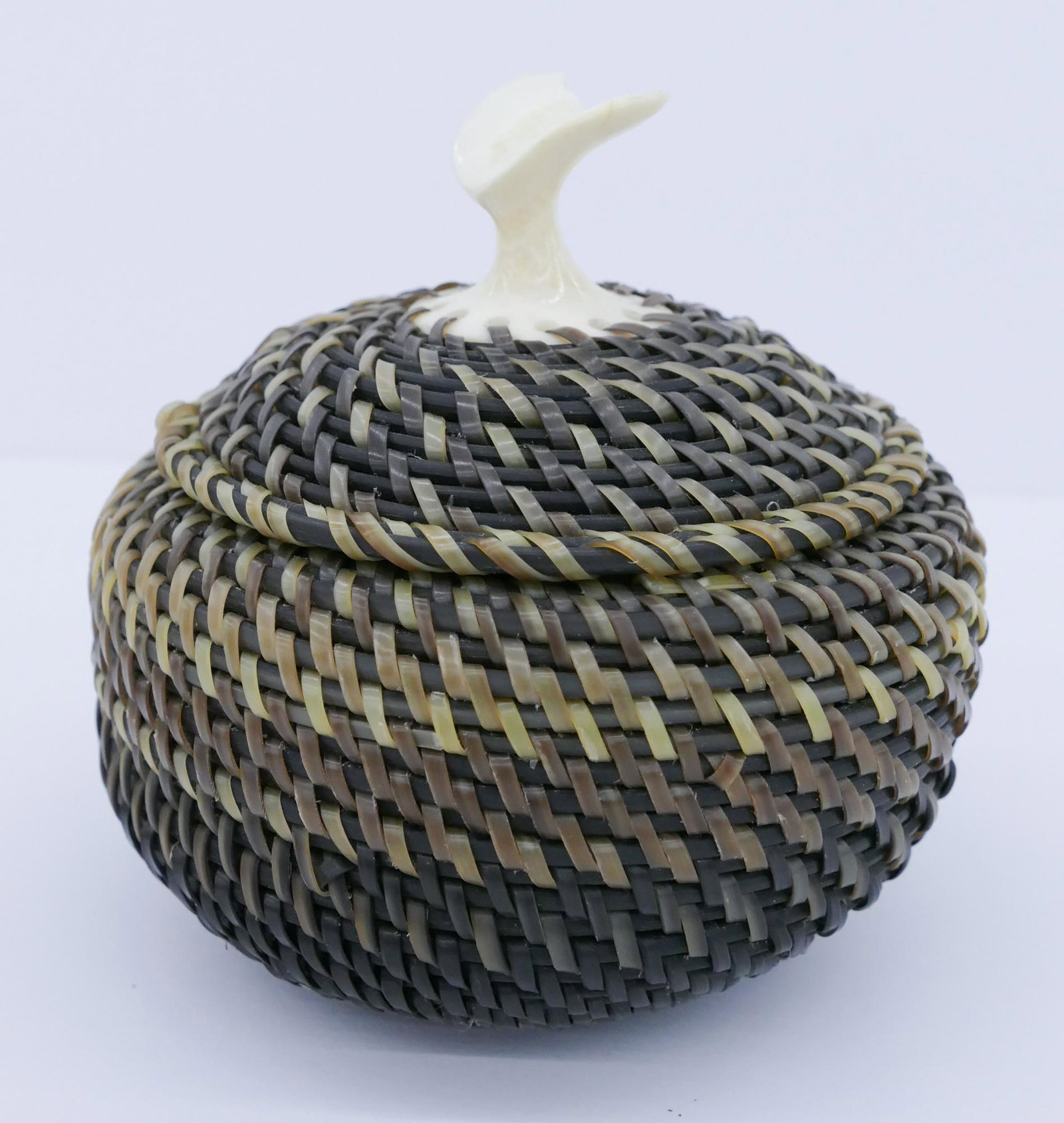 Elijah Attungana Whale Tail Baleen Basket: Elijah Attungana (1933-2011 Inuit) Whale Tail Baleen Basket 4''x4''. Woven two-tone baleen with figural whale tail finial. Initialed on interior. Excellent condition.
