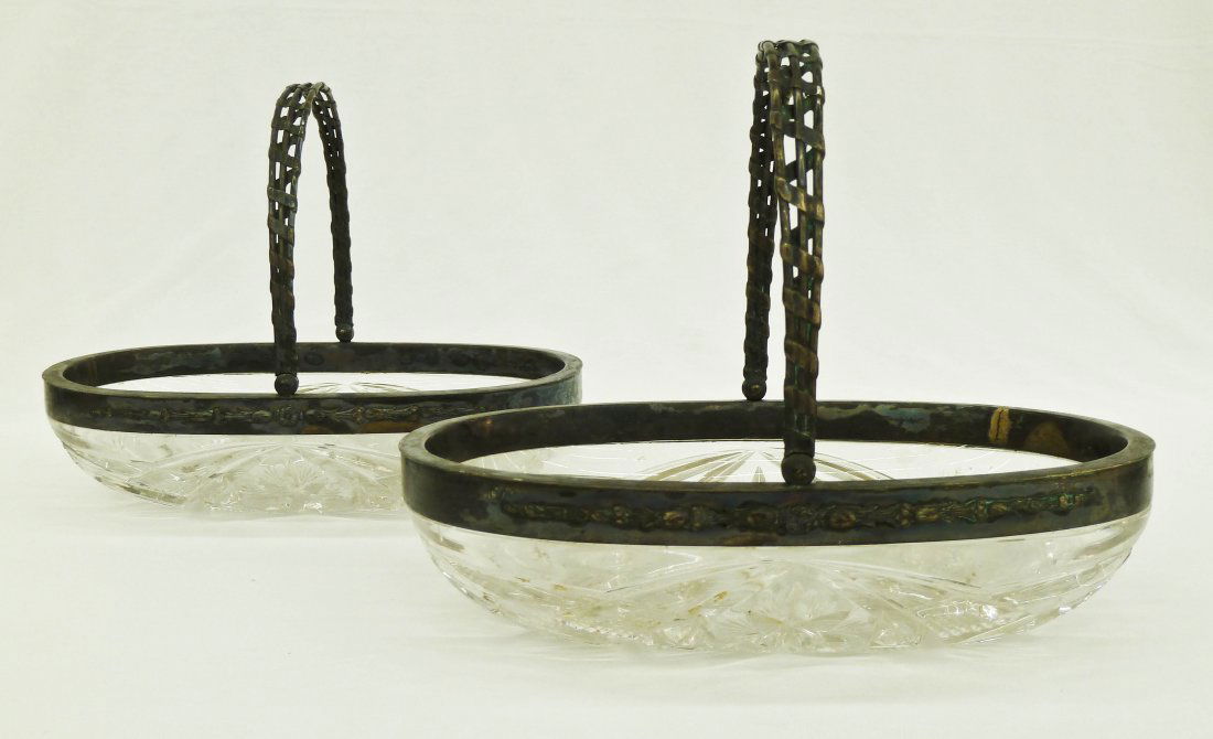 Pair Baccarat Cut Crystal Oval Baskets with Russia: Pair Baccarat Cut Crystal Oval Baskets with Russian Sterling Silver Mounts 9''x6''. Some verdigris on the silver. Both baskets have slight chipping to the bottom edges of the cut.