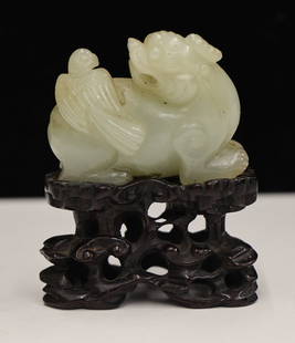 Chinese Jade Foo Lion Pebble on Stand: Chinese Jade Foo Lion Pebble on Stand 2.5''x2''. Pale celadon carved jade of a recumbent foo lion with bird. Carved rosewood fitted stand with lingzhi motif, measures 1.25''x1.75'' without. Excellent