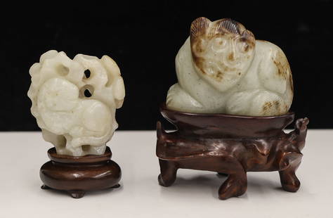 2pc Chinese Jade Animal Pebble Carvings on Stands: 2pc Chinese Jade Animal Pebble Carvings on Stands 2.5'' to 3.25''. Includes a greyish white jade recumbent foo lion with brown splashing and a pale white jade pierced lion and rock pebble. Carved