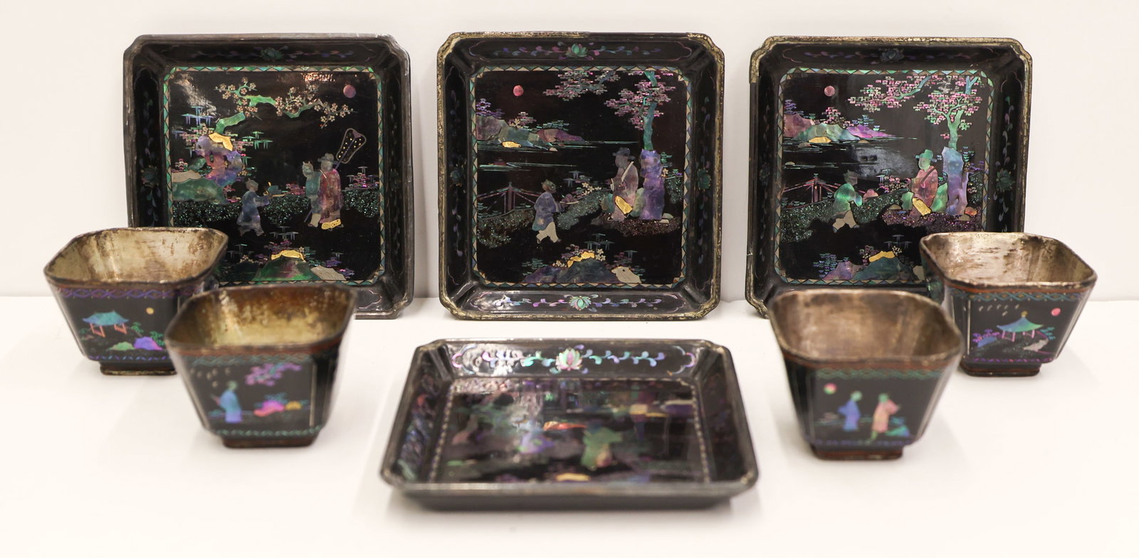 8pc Jiang Qianli Lac Burgaute Wine Cups & Trays: 8pc Jiang Qianli Chinese Lac Burgaute Silver Wine Cups and Trays 1.5'' to 4''. Includes a set of four wine cups and intricately inlaid trays over silver. Inlaid Jiang Qianli seal mark on verso of tray