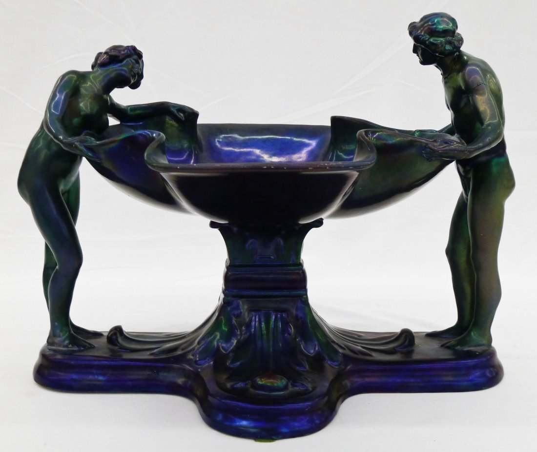 Zsolnay Blue Iridescent Figural Compote with Male &: Zsolnay Blue Iridescent Figural Compote with Male & Female Standing Nudes 7.5''x11''. Form 7855. Repairs to male's head and arm.