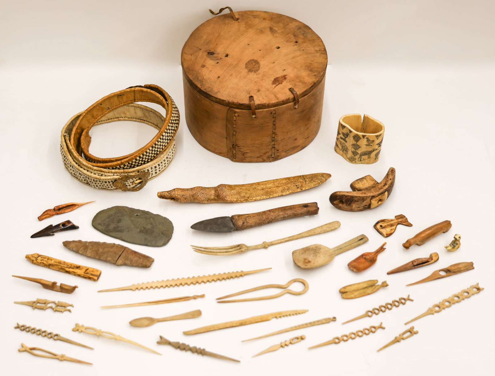 Collection of Antique Yupik Eskimo Implements: Collection of Antique Yupik Eskimo Implements 1'' to 10''. Includes (40) pieces of carved bone hair pins, utensils, harpoon points, effigies, two seal skin woven belts, and a bentwood round box. As se