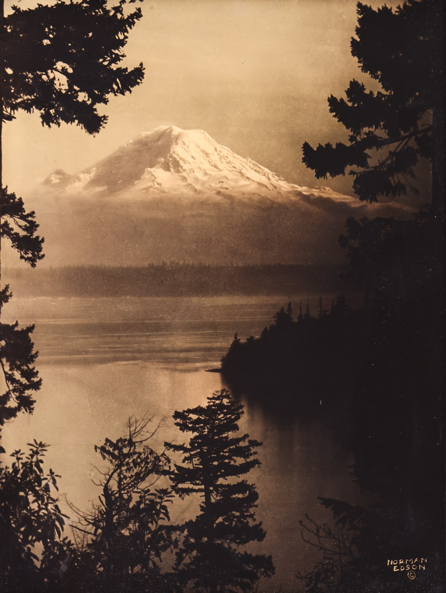 Norman Edson "Moonlight" (Mt. Rainier) Orotone Photograph: Norman Edson (1879-1968 Washington) "Moonlight" (Mt. Rainier) Orotone Photograph 10"x8" Image. A scarce version of this goldtone. Signed l.r. Original period framing 11.75"x9.75". Excellent condition.