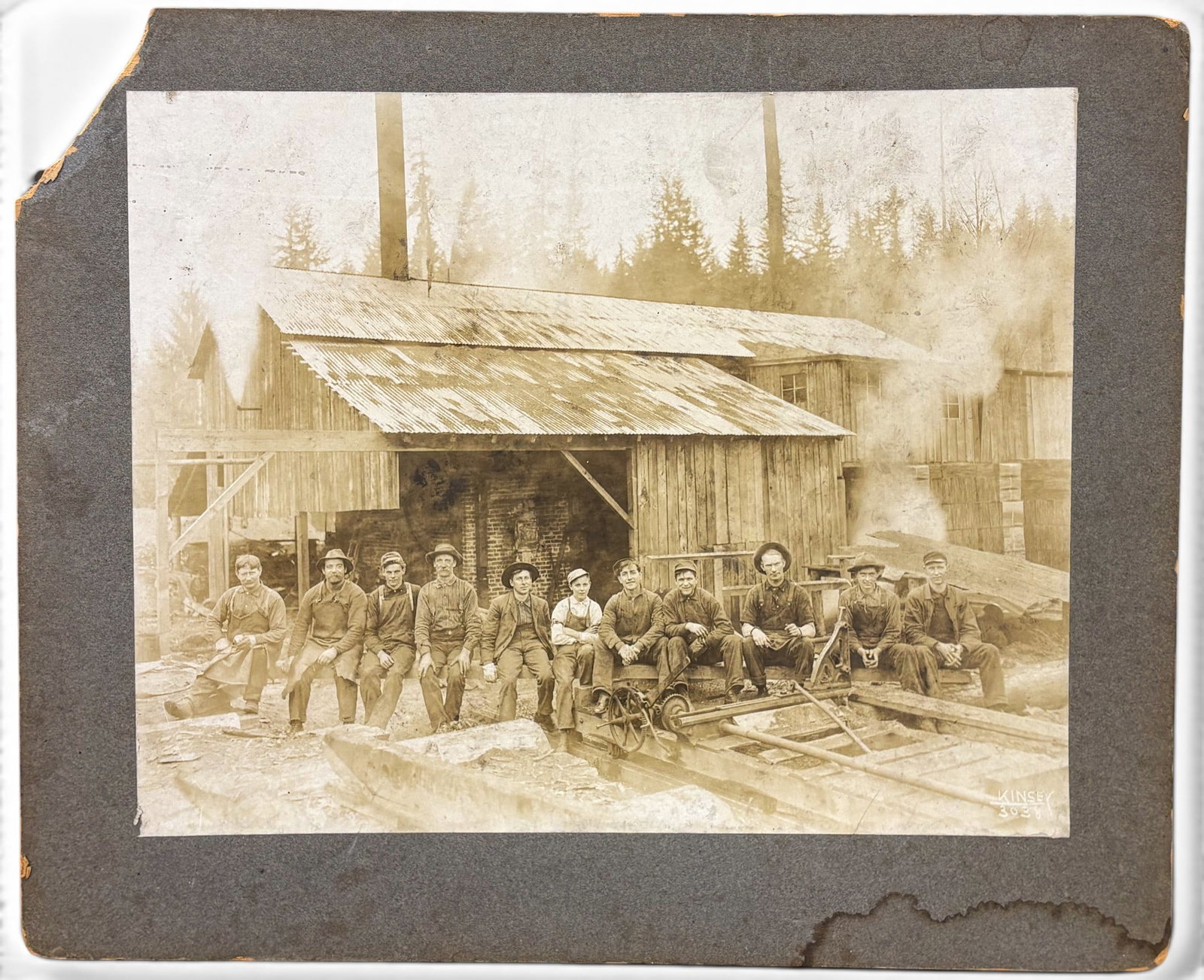 Kinsey Bros. "Loggin Boys" Albumen Photograph: Kinsey Bros. "Loggin Boys" Albumen Photograph 11"x13.5" Image 13.75"x16.75" Mounted. Signed lower right and numbered 3038. Scattered wear and foxing to photo, damage to mount.