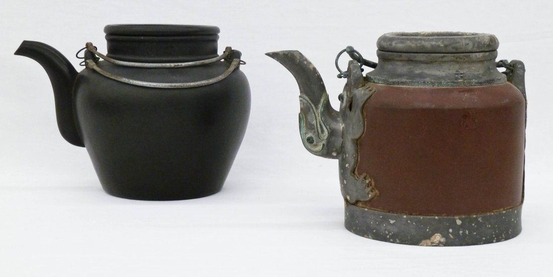 (2) Chinese Black & Red Yixing Clay Teapots. Red teapot: (2) Chinese Black & Red Yixing Clay Teapots. Red teapot has figural elephant pewter handle and coin on lid. It measures 6''x8'' and has an impressed four seal mark under base. Black teapot measures 6'