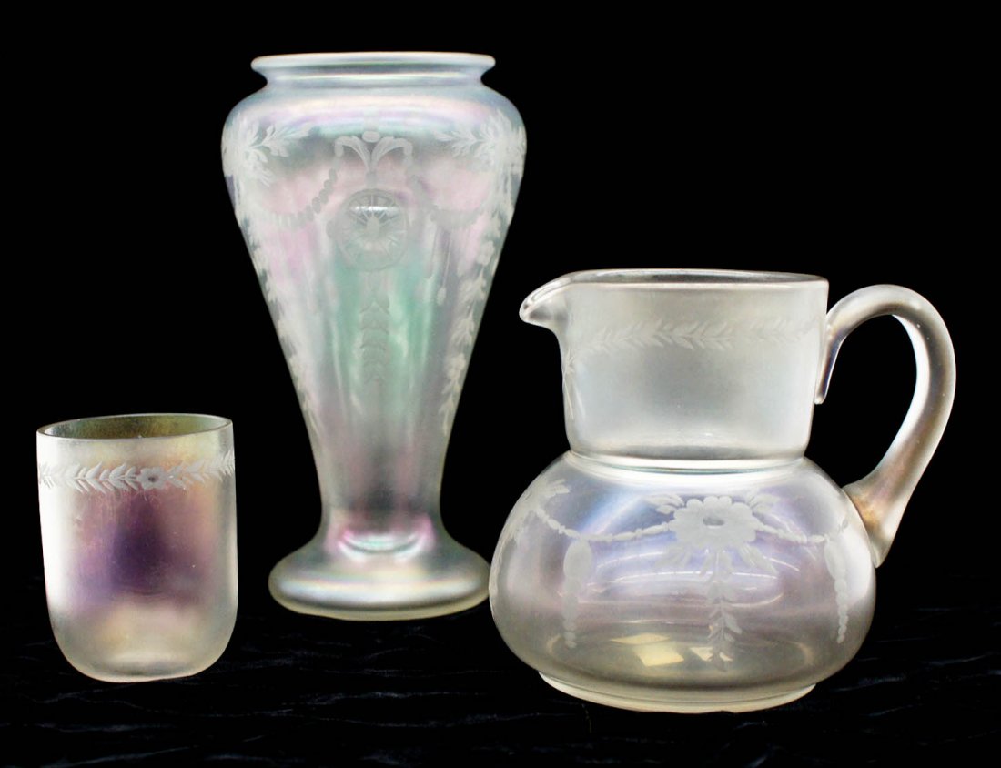 (3) Pieces Steuben Verre de Soie Iridescent Art Glass.: (3) Pieces Steuben Verre de Soie Iridescent Art Glass. Includes an etched 8''x4'' vase, a pitcher 5''x5.5'', and a small tumbler 3.25''. Each has etched floral wreath designs around exterior. Vase has