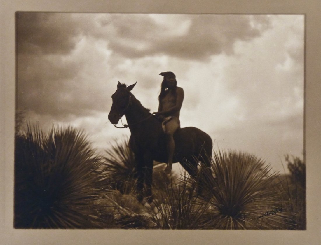 Edward S. Curtis (1868-1952 Washington) ''The Scout: Edward S. Curtis (1868-1952 Washington) ''The Scout Apache'' Platinum Border Print Photograph 5.75''x7.75'' Image. This pristine example is loose with its original 10''x12'' folio cover with title lab