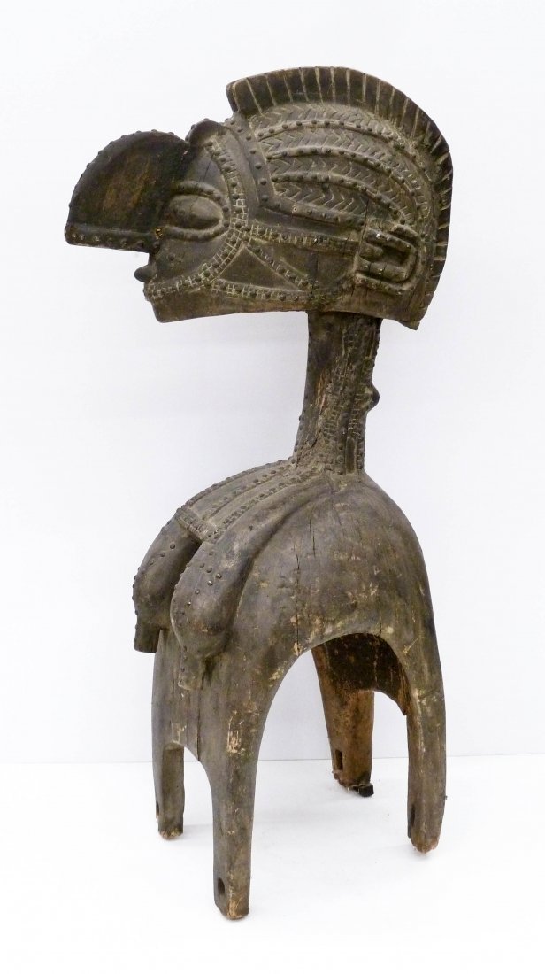 Old Baga Guinea Nimba Shoulder Mask on Stand: Old Baga Guinea Nimba Shoulder Mask on Stand 54''x25''x16''. African carved wood mask with applied metal ornaments. Overall edge wear with various age cracks to wood. Missing bottom portion of some of