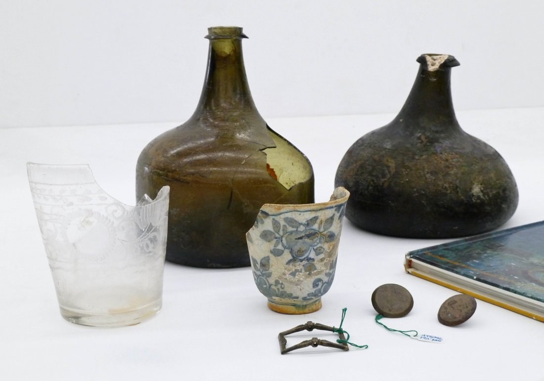7pc Dominican Republic Shipwreck Glass Bottles &: 7pc Dominican Republic Shipwreck Glass Bottles & Relics. Includes two green glass bottles 5.5'' to 6.5'' in height, a porcelain and glass cup shard, two brass buttons, and a brass small buckle. From t