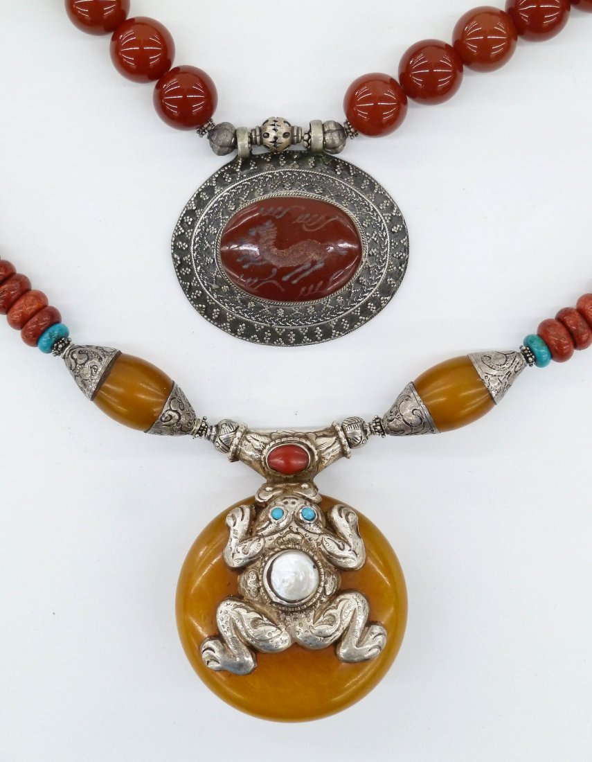 2pc Tibetan Carnelian & Copal Amber Necklaces. Includes: 2pc Tibetan Carnelian & Copal Amber Necklaces. Includes frog/fish disc pendant necklace 26'' with a 2.25'' pendant. Consisting of copal amber, turquoise, coral, and mother of pearl. Carnelian necklace