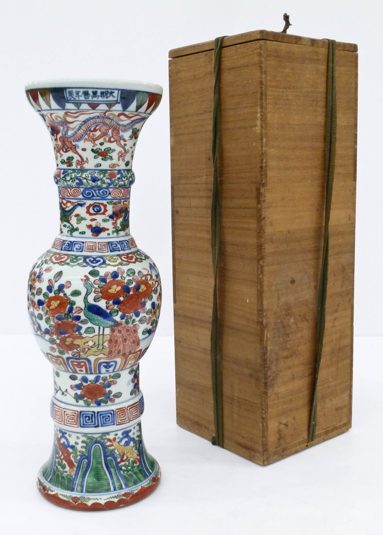 A Japanese Wucai Gu Beaker Porcelain Vase 18''x6''. A: A Japanese Wucai Gu Beaker Porcelain Vase 18''x6''. A japanese copy of a Chinese Ming vase that bears a six character Wanli mark on top rim. Blue underglaze with polychrome overglaze enamels. It has f