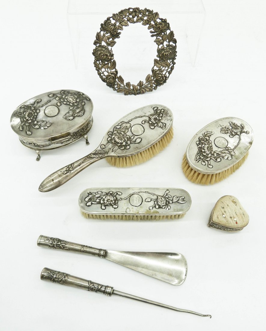 9pc Chinese Export Silver Dresser Set. Includes three: 9pc Chinese Export Silver Dresser Set. Includes three brushes, a dresser box, a pierced standing floral frame, a pin cushion, a belt hook, and a button hook. Sizes range from 2'' to 10'' in length. Th