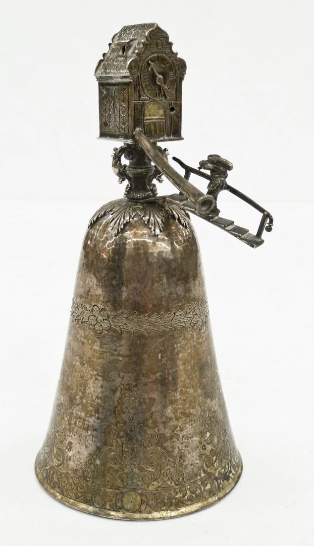 An Early Dutch Silver Wager Cup 8.75''x4''. Figural: An Early Dutch Silver Wager Cup 8.75''x4''. Figural windmill clock finial with hand worked decoration. Also an ornament of a man walking up stairs. Bell shaped cup has engraved floral motifs with two 