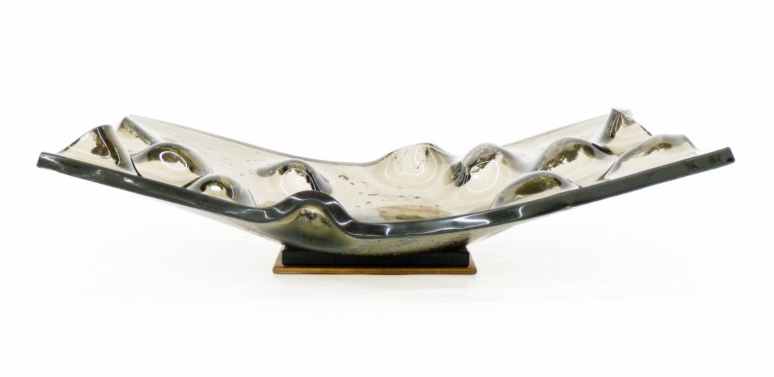 Dennis Evans (b.1946 Washington) Sculptural Glass Bowl: Dennis Evans (b.1946 Washington) Sculptural Glass Bowl 4.5''x20''x12''. Formed smoke glass centerpiece bowl with gold painted steel and beveled black glass base. Likely executed with wife, Nancy Mee.
