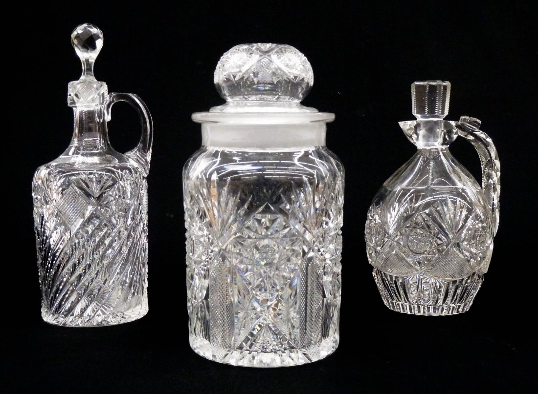 3pc Old Brilliant Cut Glass. Includes a covered jar: 3pc Old Brilliant Cut Glass. Includes a covered jar 9''x4.75'', a handled whiskey or rum jug 8''x4.5'', and a tall handled jug 10''x4''. All have no visible signatures. Each jug has a few small edge c