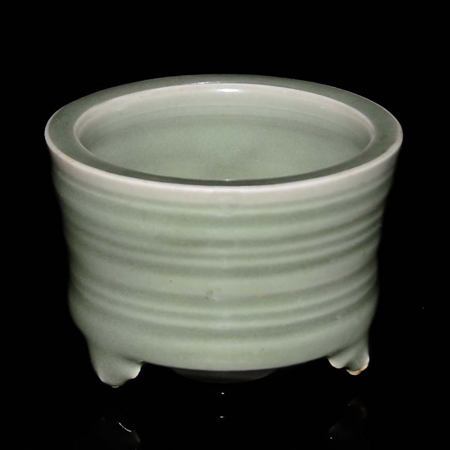 A Celadon Longquan Tripod Brush Washer: 龍泉窯圓底三足洗 A Celadon Longquan Tripod Brush Washer The ribbed body encircled by a raised groove, atop three bracket feet, the foot rim left unglaze