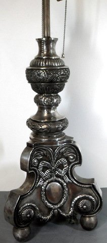 Colonial Spanish Revival Silver Lamp: Colonial Spanish Revival Silver Accent Lamp Ornate hand chased silvered trifid base table lamp with scroll and medallion panels on bold ball feet. 25" tall Fabric shade.