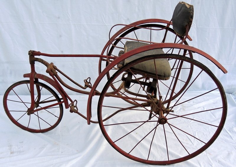 Rare Child's Wire Wheel Velocipede: Original condition red painted surface, iron push peddles, canvas seat on back, wooden hand grips. Circa 1900. American National Co metal tag. 38" overall length x 25" tall at seat crest rail.