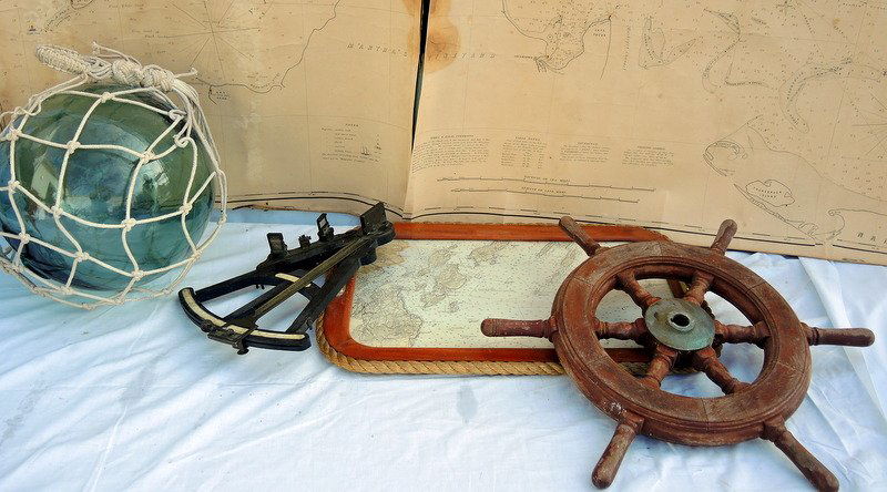 Antique Nautical Objects: Early ebony on ivory English sextant. Appears complete. 15" long. Six spoke wooden ship's wheel, weathered mahogany finish. From old lobstering craft. 21" diameter. Early blue canvas sea chart, 1858 V