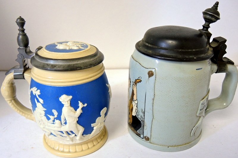 Two German Mettlach Steins: #2211 molded 1 L, bowling and tavern scene. #1645, incised, troubadour. Thumb back pewter finial slightly bent backwards