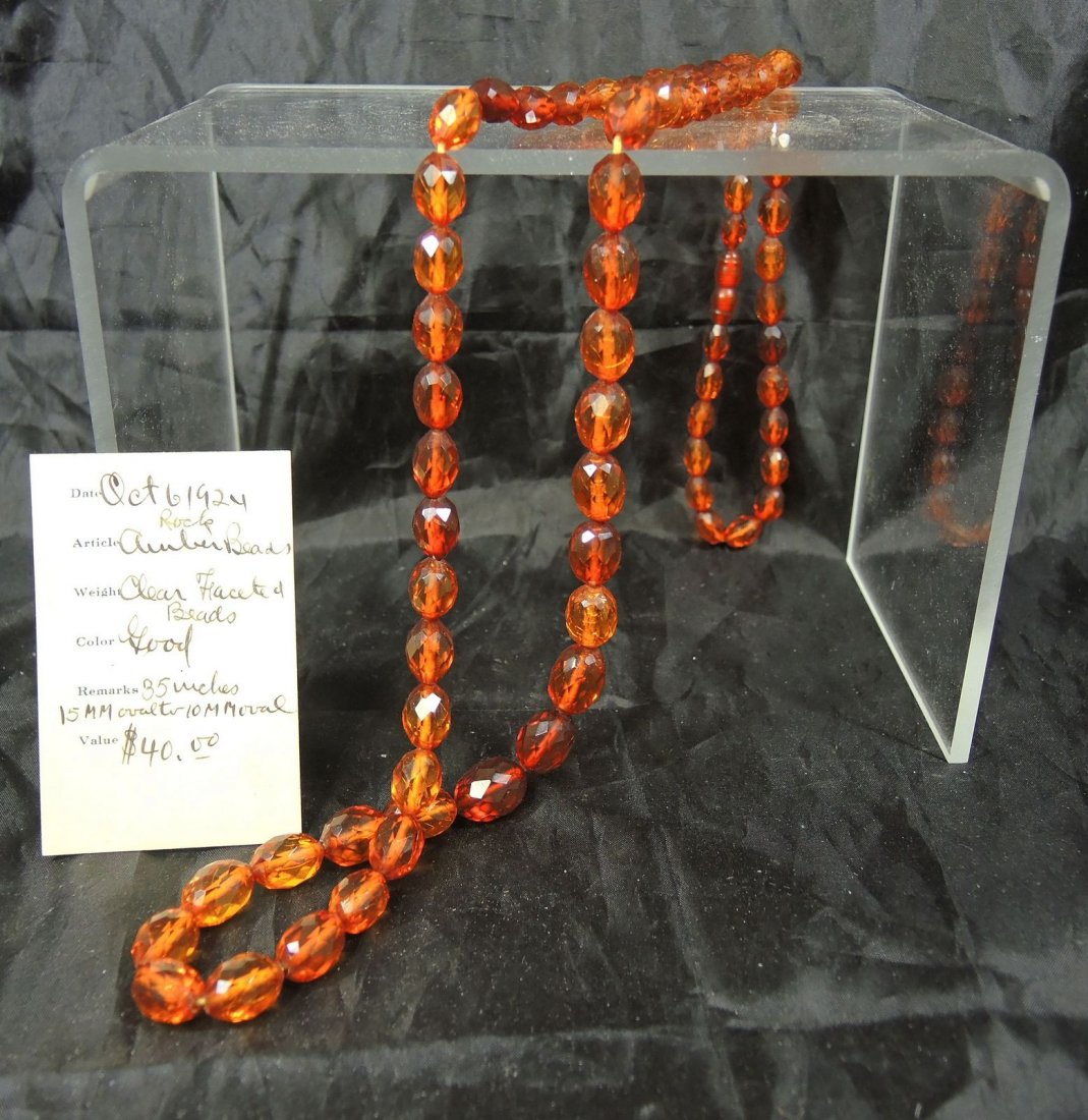 1920's Rock Amber Beads: Rock amber bead necklace features 15MM oval to 10MM oval beads. 35" length. Original box and note.