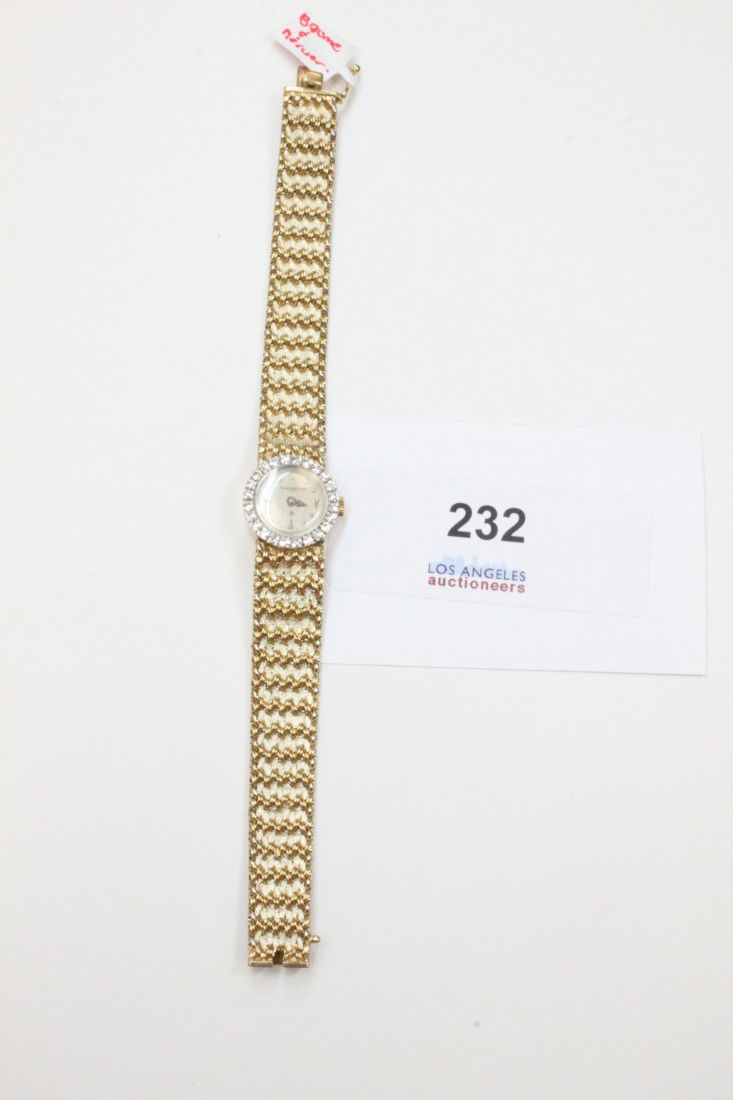 Baume & Mercier Lady's watch: Baume & Mercier Geneve 14k gold lady's wrist watch. Diamond lining around circular face. Designer mark engraved on back of face.