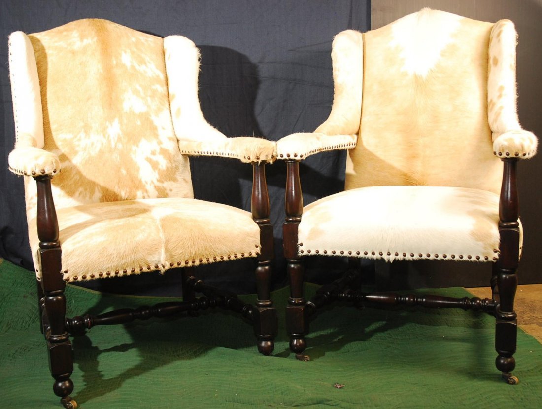 Pair of Deluxe Western Style Cowhide Chairs: Deluxe Southwest / western style Wingback arm chairs, upholstered with real cowhide & nailhead trim, solid carved wood frame finish in dark espresso. Dimensions 45'H x 30"W x 25"D