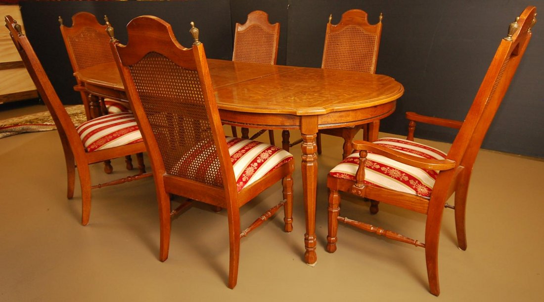 Vintage Dining Room Set: 6 wooden chairs with wicker backing and metal accents. Chairs are reupholstered. One chair is missing one post, slight scratches on wooden table surface. Burl finish on table top. 42" W 62"L.