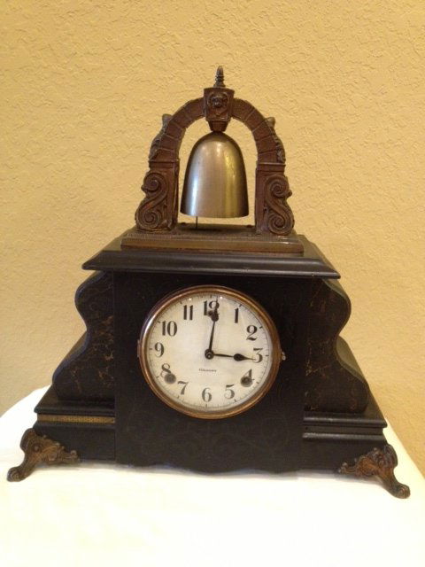 William Gilbert Curfew Mantle Clock: Large arched bell on top, faux marble wood case with ormolu feet. Paper dial marked Gilbert. Currently running however not guaranteed to continue. Missing back door. 17"H x 17"W x 6"W.