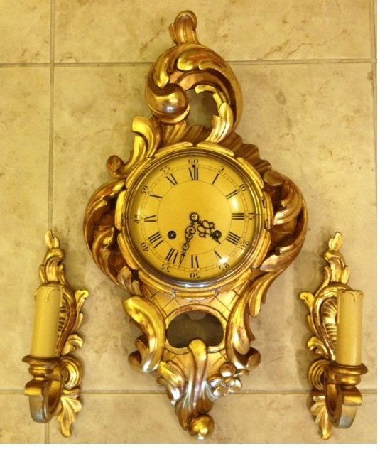Swedish Gilt Wood Cartel Clock and Sconces: Three pieces to include carved and gilt wood Rococo Revival case cartel wall clock time and strike movement. Measures 22"H x 12"W x 5"D. Sold with matching single light electric sconces 11"H x 3"D x 5