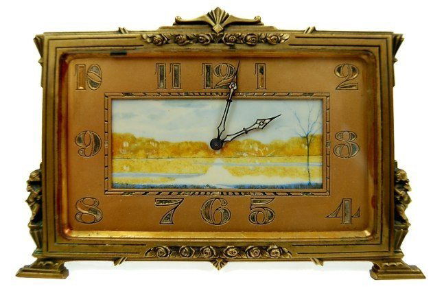 J E Caldwell & Co. Art Deco ivory face clock: J. E. Caldwell & Co. Art Deco hand painted ivory face gilt bronze easel back clock having large Arabic markers in a gilt bronze case accented with flute-playing Putti, measuring 4.25" x 6.75", beveled