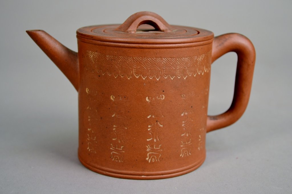 Yixing Teapot: A nice teapot with impressed designs and writing. The lid has bats stamped into it. IT has its orginal strainer. 6 1/4" X 4".