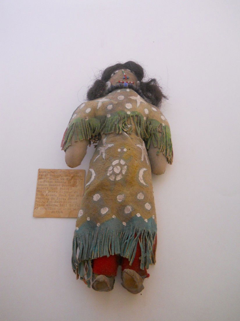 "A-NOG-I-TE" GHOST DANCE DOLL: "THE DOUBLE FACED WOMAN" OR GHOST DANCE DOLL, FULL BRAIN TANNED DEERSKIN, PAINTED ON BOTH SIDES, SEED BEADED FACE WITH HUMAN HAIR. APPROX 11"LONG X 5.5"WIDE ARM TO ARM