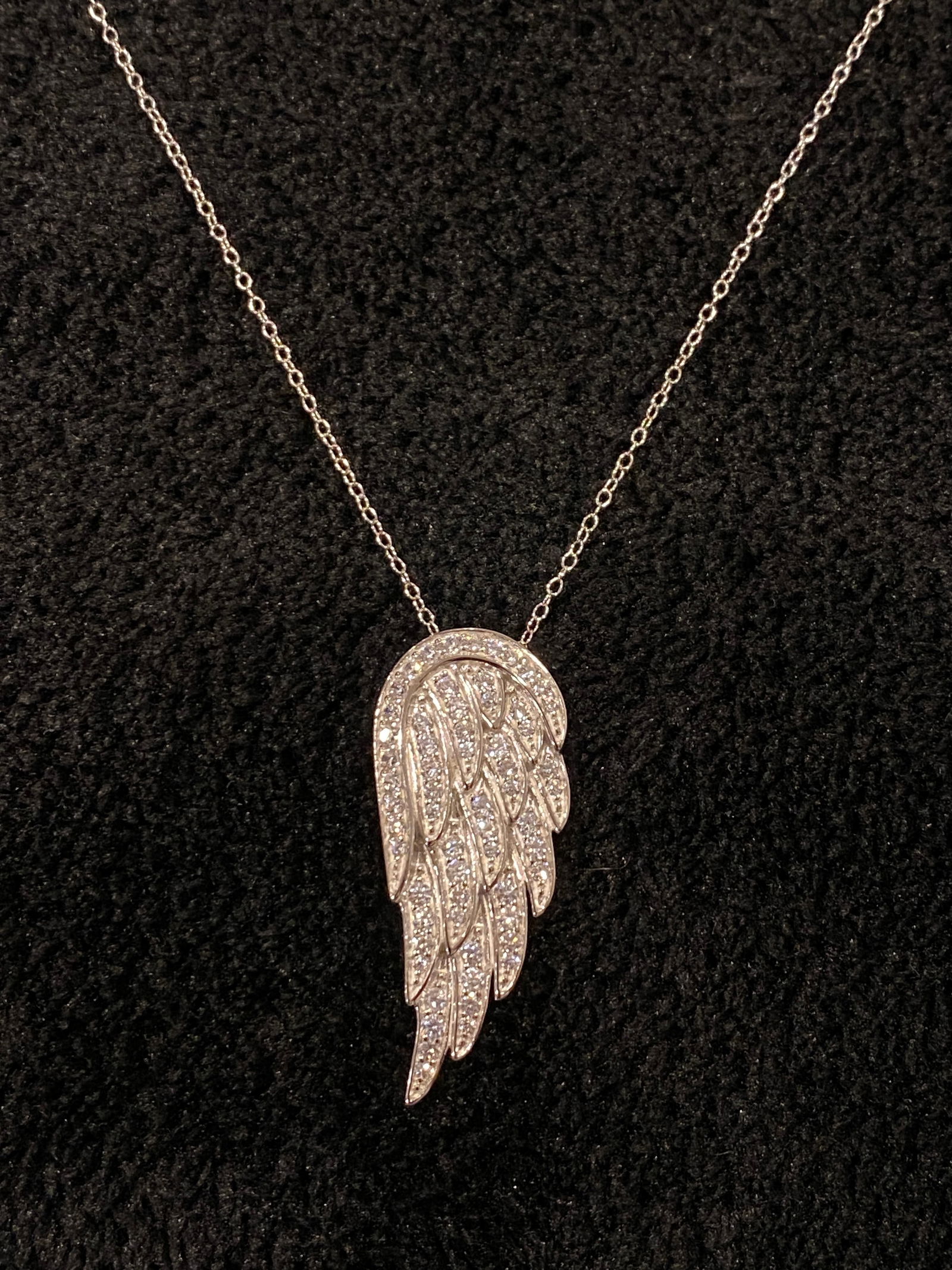 White Cubic Zirconia Rhodium Over Sterling Silver Angel Wing Pendant With Chain 1.85ctw: White diamond simulant 1.85ctw round rhodium over sterling silver angel wing pendant with 18" chain and has lobster claw clasp closure. Measures approximately 1 3/8"L x 9/16"W with a 2 mm bail. Metal