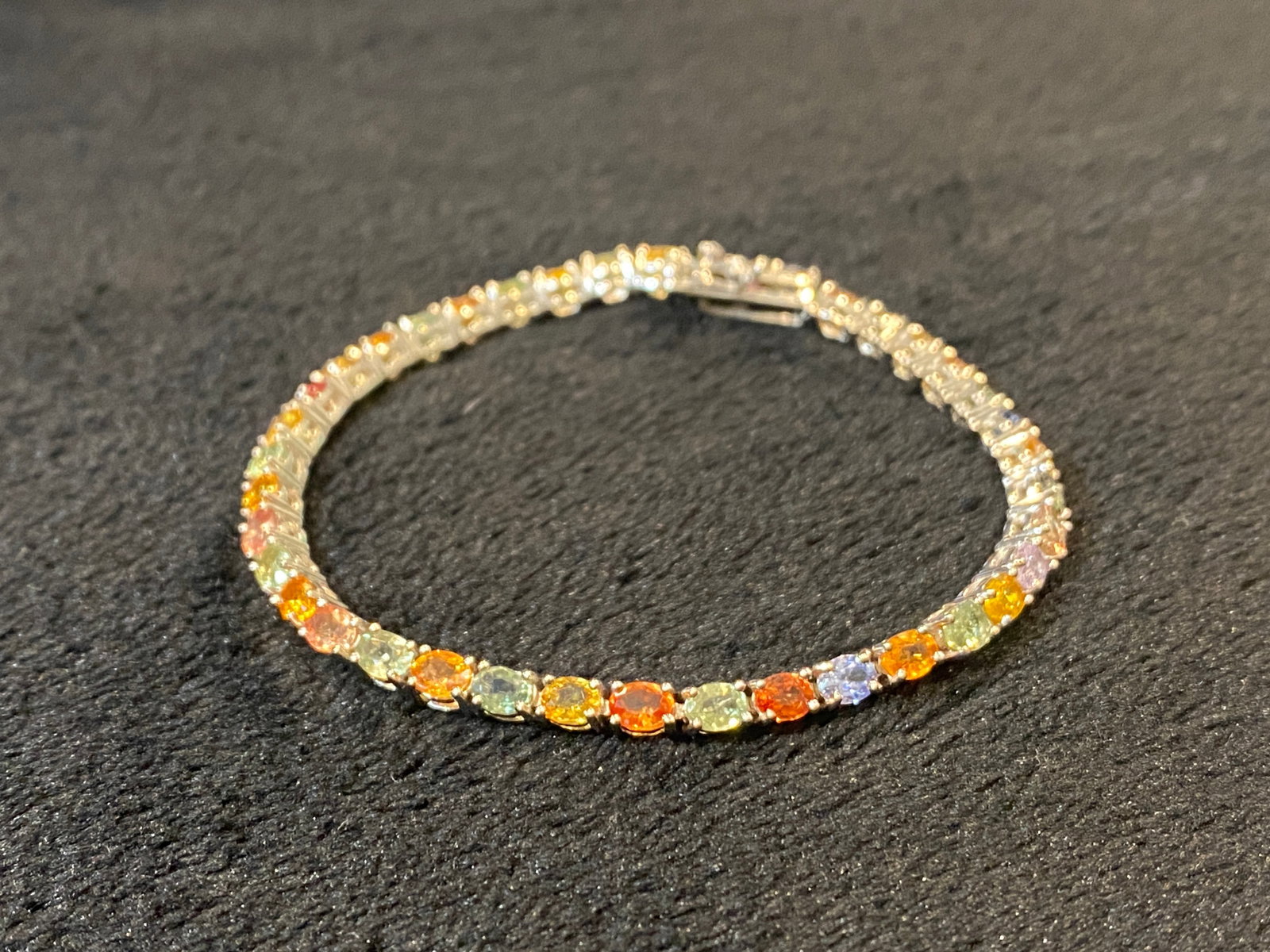 Multi-Sapphire Rhodium Over Sterling Silver Tennis Bracelet. 7.5in long.: Multi-Sapphire Rhodium Over Sterling Silver Tennis Bracelet. 7.5in long. Oval multi-sapphire rhodium over sterling silver tennis bracelet. Measures approximately 1/8"W. Hidden stainless steel box clas