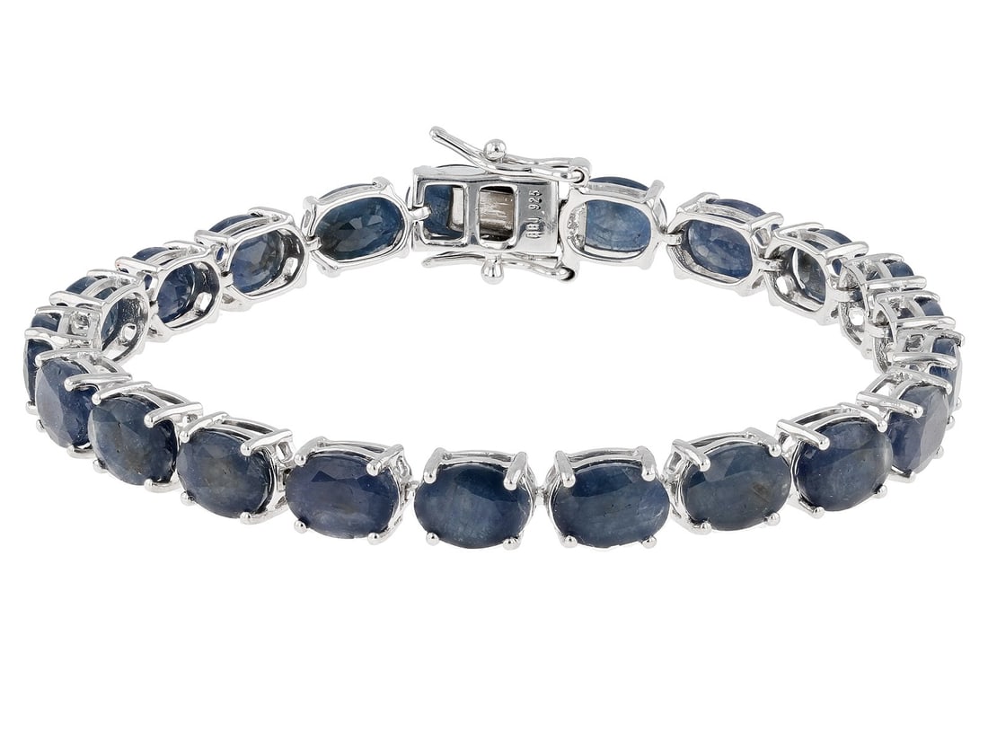 Blue Indian Sapphire Rhodium Over Sterling Silver Bracelet 31.23ctw: Blue Indian Sapphire Rhodium Over Sterling Silver Bracelet 31.23ctw. 31.23ctw Oval Indian Blue Sapphire Rhodium Over Sterling Silver Tennis Bracelet. Measures approximately .24"W. Hidden box clasp clo