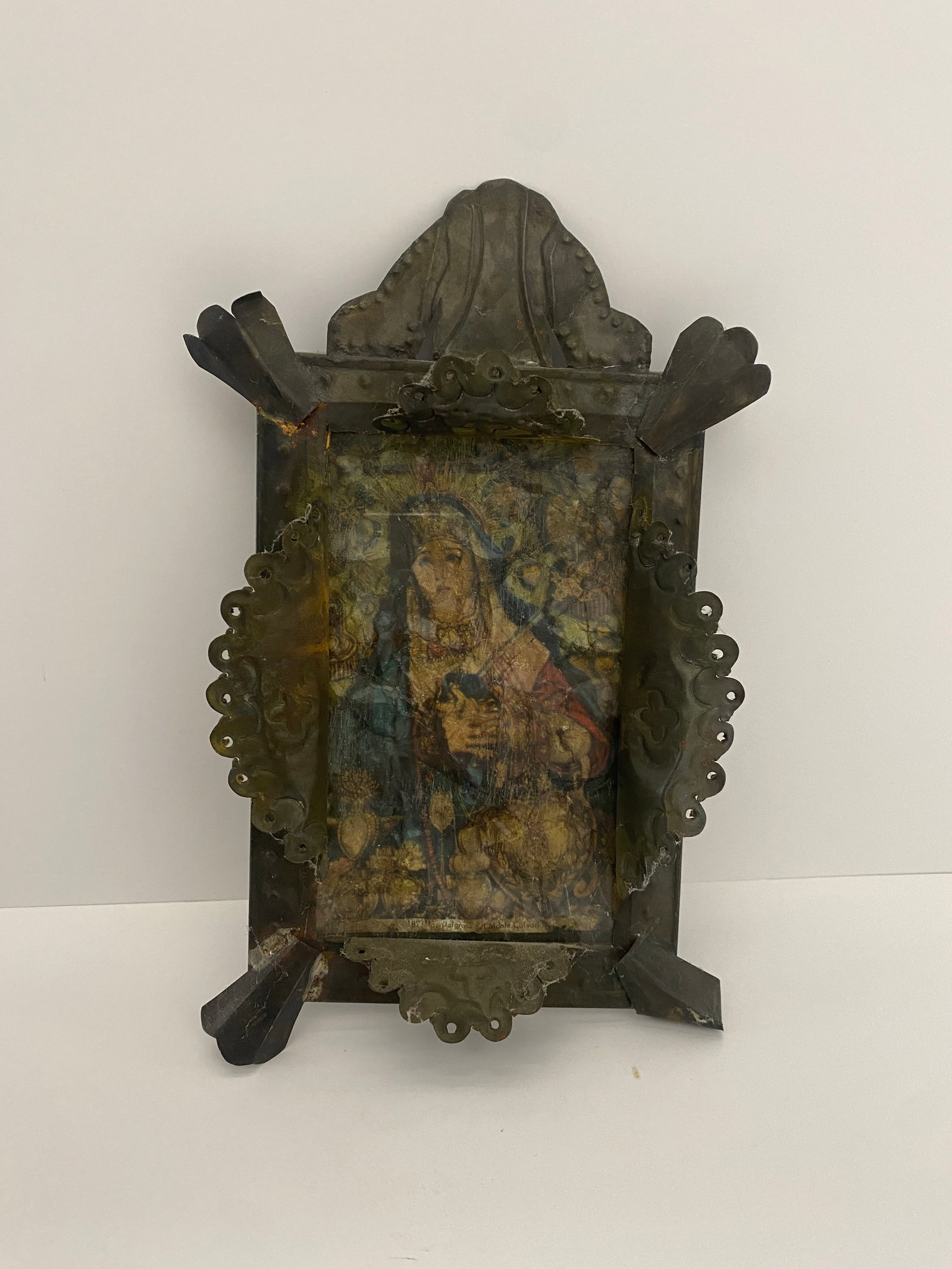 Retablos of the Virgin Mary in a Tin Frame: This exquisite religious painting features a beautifully detailed depiction set within an ornate metal frame. The artwork showcases a vibrant and sacred image, making it an ideal addition to any colle