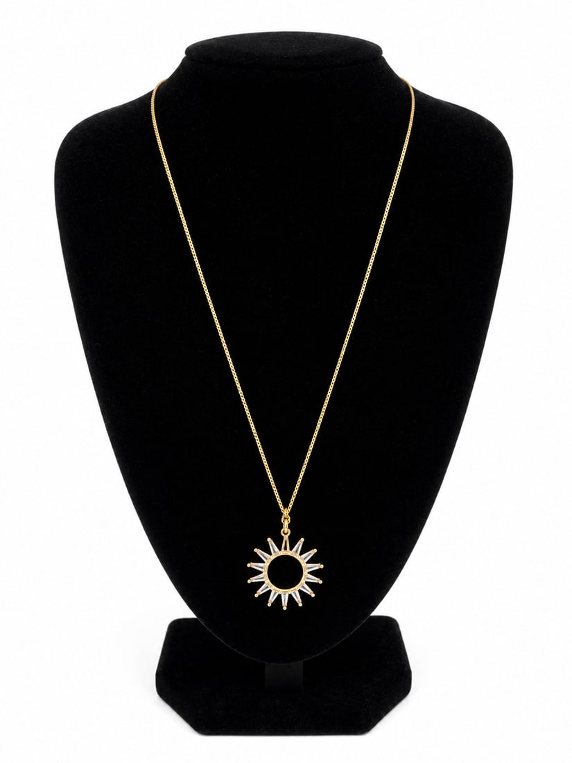 Gold Sunburst Pendant Necklace: Gold chain necklace featuring a sunburst-style pendant with clear baguette-style stones and a dark center. Ships from Newport Beach, CA.Proceeds go to Hoag Hospital Charitable Foundation.