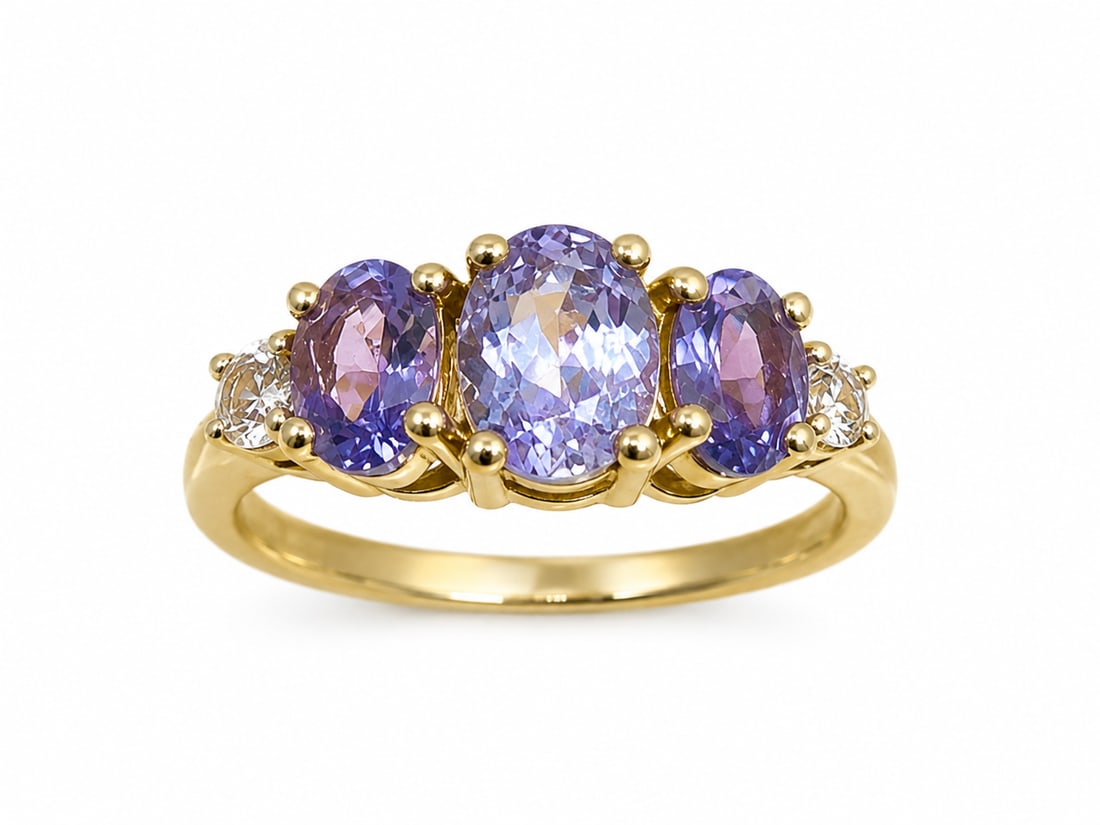 Gold Ring with Tanzanite Oval Stones & Clear Cubic Zirconia Accents: Gold ring featuring three oval violet-blue stones with a tanzanite appearance, accented by clear round cubic zirconia stones on each side. The larger center stone is flanked by two matching oval stone