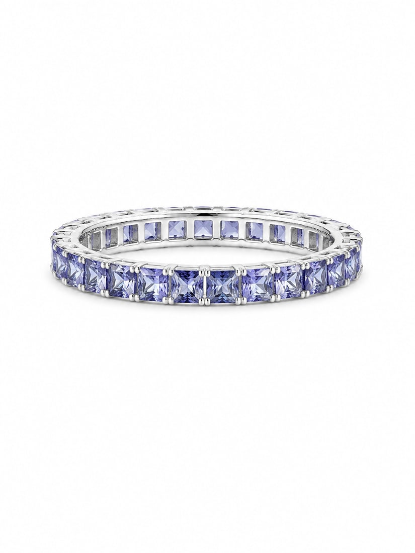 Silver Eternity Ring with Tanzanite Princess-Cut Stones: Silver eternity-style ring featuring a continuous row of square princess-cut violet-blue stones with a tanzanite appearance, individually prong set around the band. Size 9.Ships from Newport Beach,