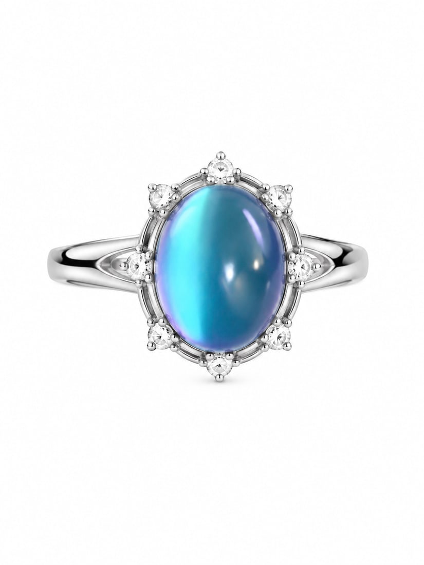 Silver Blue Moonstone & Clear Stone Oval Halo Ring: Silver ring featuring a large oval blue moonstone cabochon with luminous blue and violet iridescence. The center stone is framed by round clear accent stones in a delicate halo setting, with additiona
