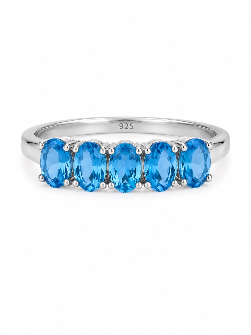 Sterling Blue Topaz Five-Stone Oval Band Ring: 925 sterling silver ring featuring five faceted oval-cut blue topaz stones arranged across the front of the band. Each vivid blue gemstone is individually prong-set in a polished silver setting, creat