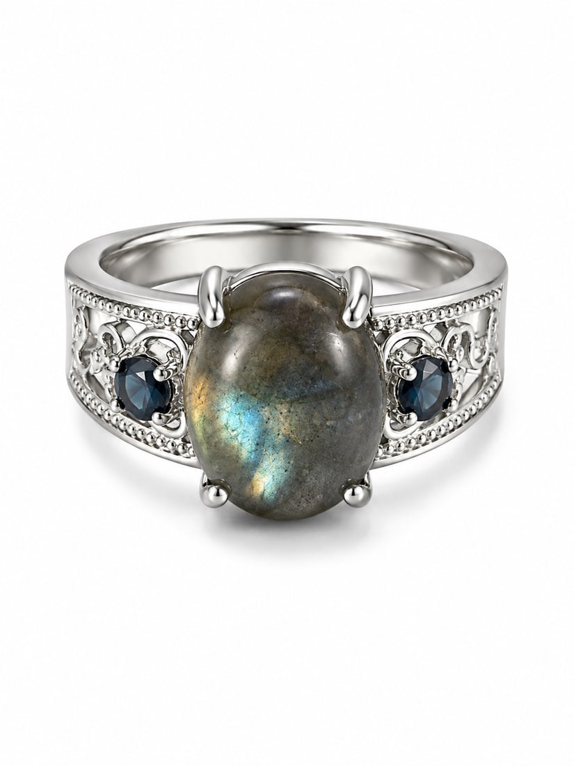 Labradorite & Blue Sapphire 925 Sterling Silver Filigree Ring: Sterling silver ring featuring a large oval labradorite center stone with blue-green iridescent flashes, accented by deep blue sapphire stones on each side. Ornate openwork filigree detailing and bead