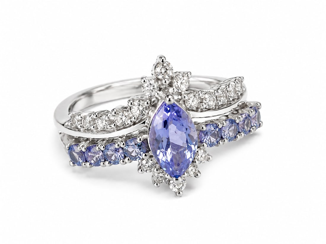 Tanzanite Marquise 925 Sterling Silver Statement Ring: Sterling silver ring featuring a striking marquise-cut tanzanite center stone surrounded by sparkling white CZ accents. Additional violet-blue tanzanite stones sweep across the lower band, while the
