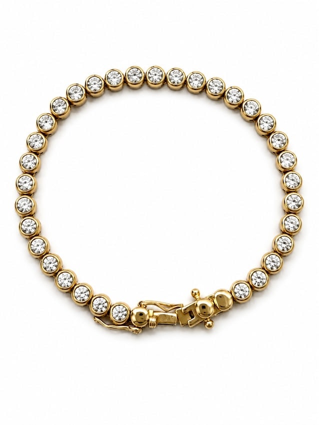 Gold Tennis Bracelet with Round Moissanite Stones: Gold tennis bracelet featuring a continuous row of round clear stones with a moissanite appearance, each set in an individual round setting. Finished with a box clasp and safety closure. Ships from