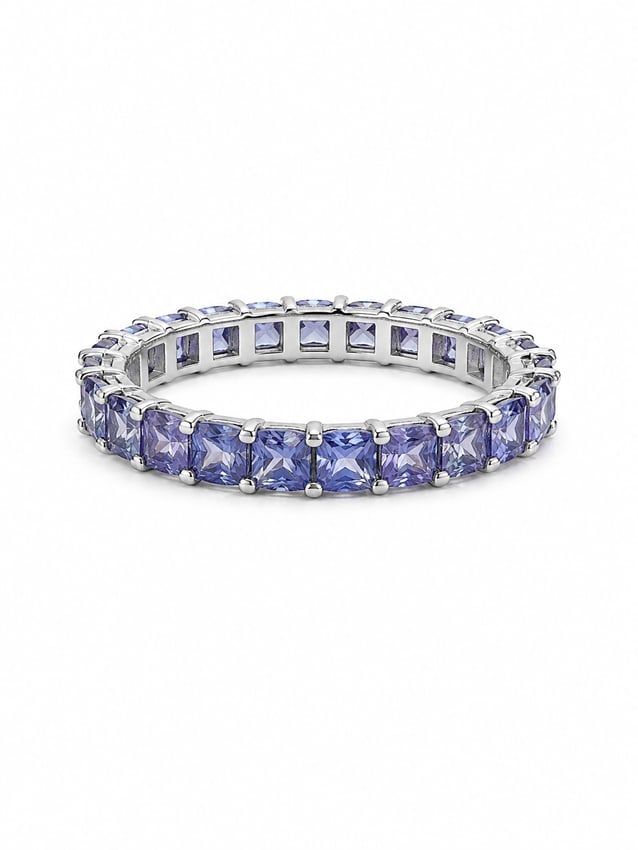 Silver Eternity Ring with Tanzanite Princess Cut Stones: Silver eternity-style ring featuring a continuous row of square princess-cut violet-blue stones with a tanzanite-like appearance, individually prong-set around the band. Ring size 9. Ships from Newpor
