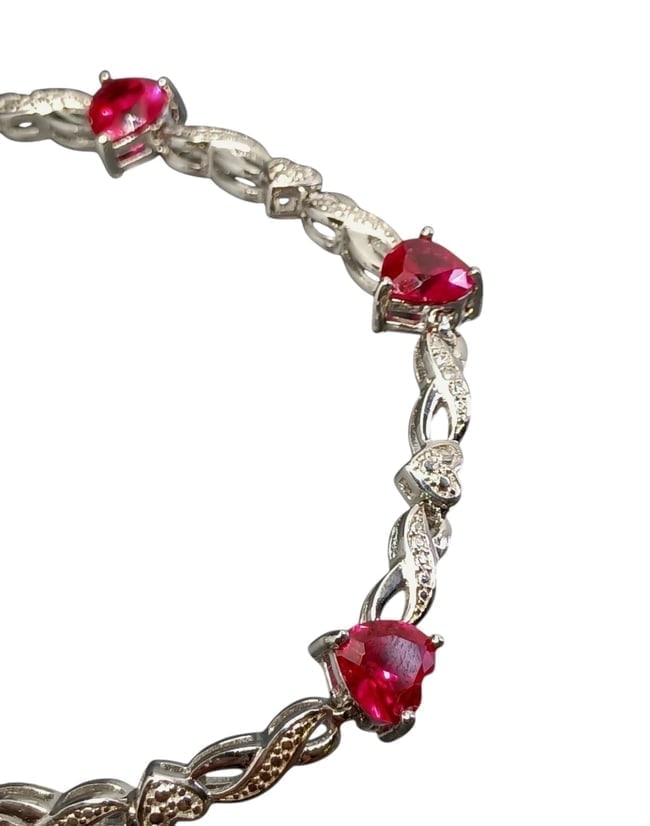 7.5" Lab-Created Ruby Heart & Ribbon Bracelet in .925 Sterling Silver: Ruby Heart Ribbon Bracelet A romantic Valentine's design by BBJ featuring lab-created ruby hearts intertwined with a sterling silver ribbon motif. Length: 7.5 Inc